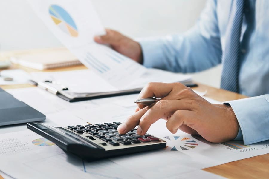 businessman holding a paper while using calculator