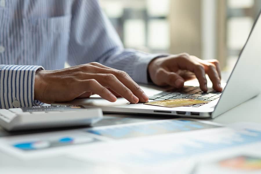 businessman working on laptop, calculator and atm cards