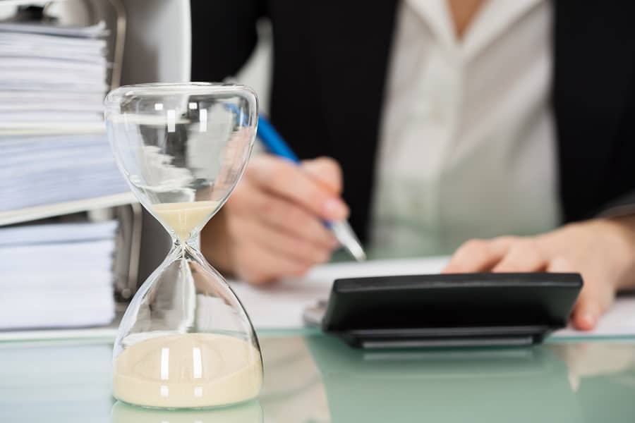 businesswoman is  working on financial on calculator, document and hourglass