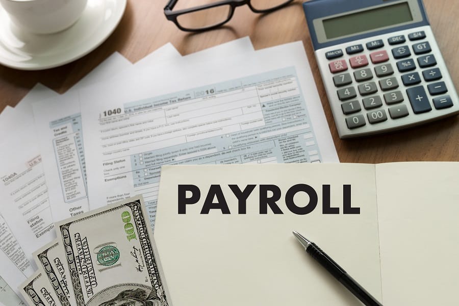 payroll in words, calculator, pen, bills and forms